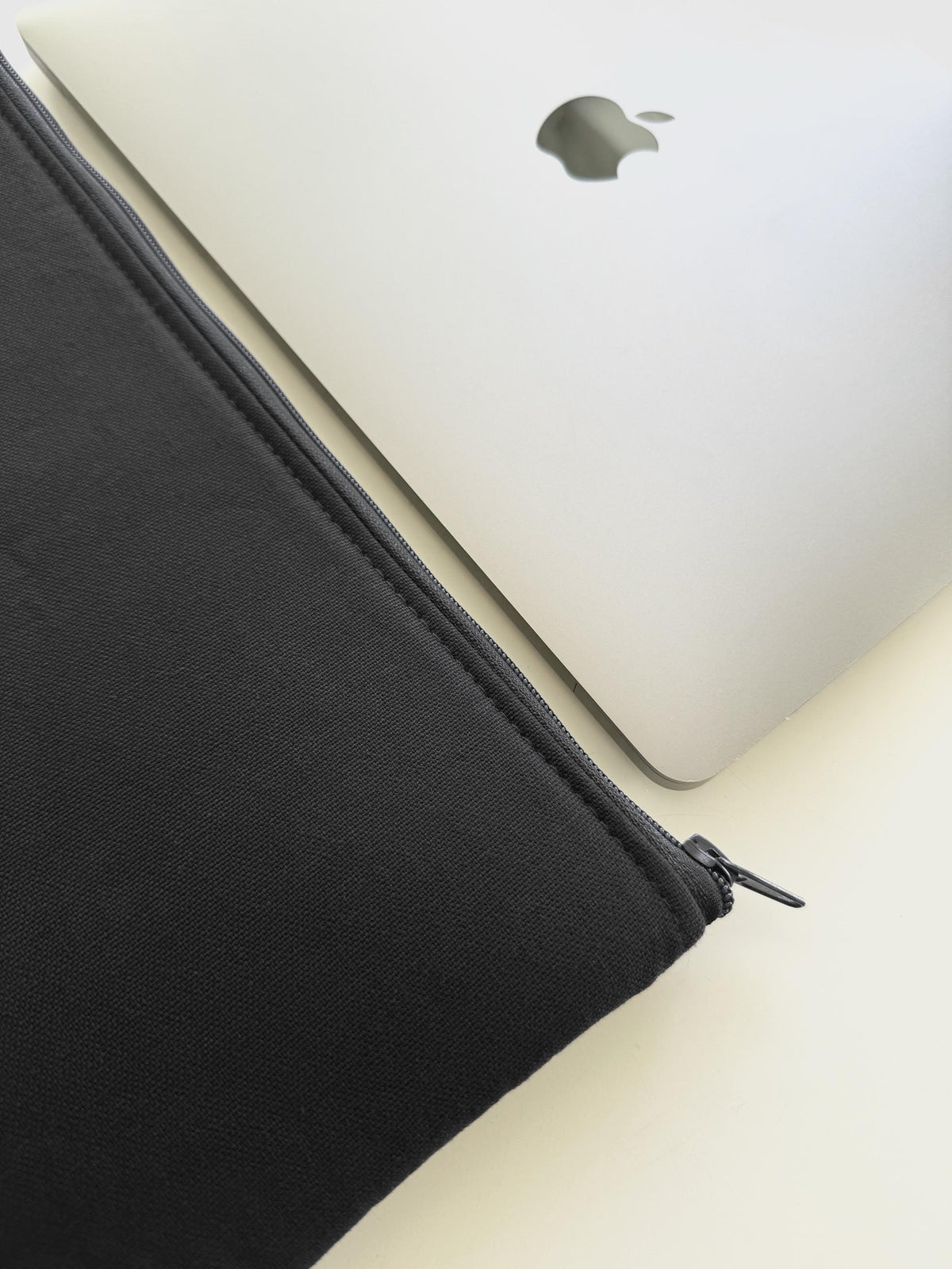 Schwarze Laptophülle aus Canvas neben MacBook, handgemacht in Hamburg