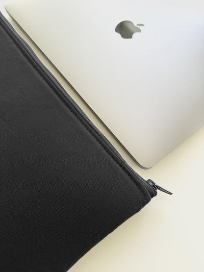 Schwarze Laptophülle aus Canvas neben MacBook, handgemacht in Hamburg